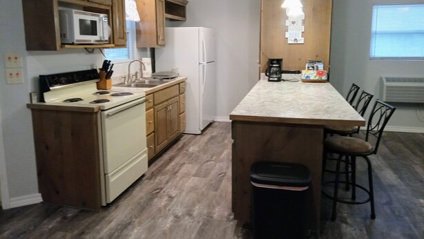 A kitchen with wooden cabinets, a white refrigerator, a stove, and a marble countertop.