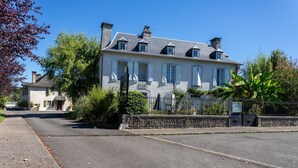 Un grand bâtiment blanc, doté de nombreuses fenêtres et d’un mur de pierre à l’avant.