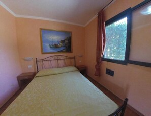 Une chambre à coucher avec un lit, un tableau, une fenêtre avec des rideaux et une table de chevet.