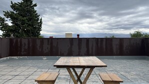 Eine Dachterrasse mit einem Holztisch und zwei Bänken.