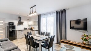 Una cocina moderna con comedor, un televisor de pantalla plana y un sofá.