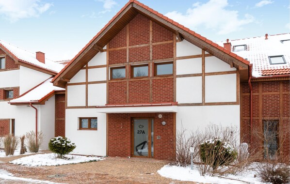 A two-story building with a brick facade and white trim, featuring a large entrance with a glass door marked "27A".
