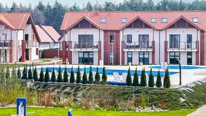 Una hilera de casas modernas con tejados de tejas rojas, una piscina y setos cuidadosamente recortados.