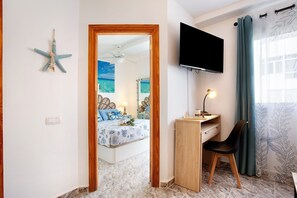 Ein Schlafzimmer mit Bett, Schreibtisch, Stuhl, Fernseher und einer Meerstern-Dekoration.