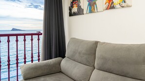 A beige sofa in a room with a view of the sea through a balcony railing. - Apartment 'Las Damas 10' with Sea View, Wi-Fi and Air Conditioning (Benidorm)