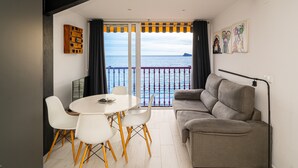 A room with a balcony, a sofa, a dining table with chairs, and artwork on the wall. - Apartment 'Las Damas 10' with Sea View, Wi-Fi and Air Conditioning (Benidorm)