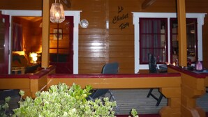 A wooden interior with a sign reading 'Le Chalet Roy' and a seating area with a table and chairs. - Chalet Le Roy in Mauroux – Relaxation, Nature & Family Fun! (Mauroux)