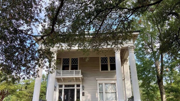 A two-story building with a balcony, large columns, and a brick foundation. - Light-Filled Loft in 1905 Belhaven Historic Home (Jackson)