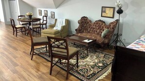 A spacious living room with a high ceiling, a dining area with a round table and chairs, a sofa, and a floor lamp. - Light-Filled Loft in 1905 Belhaven Historic Home (Jackson)