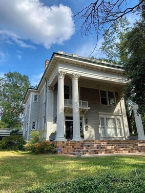 Stunning two-story building with a central entrance and columns, set amidst a beautifully manicured lawn.