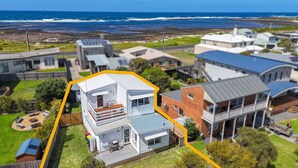 Un quartier résidentiel avec des maisons, une vue dégagée sur l’océan et une propriété mise en valeur, dotée d’une terrasse et d’un garage.