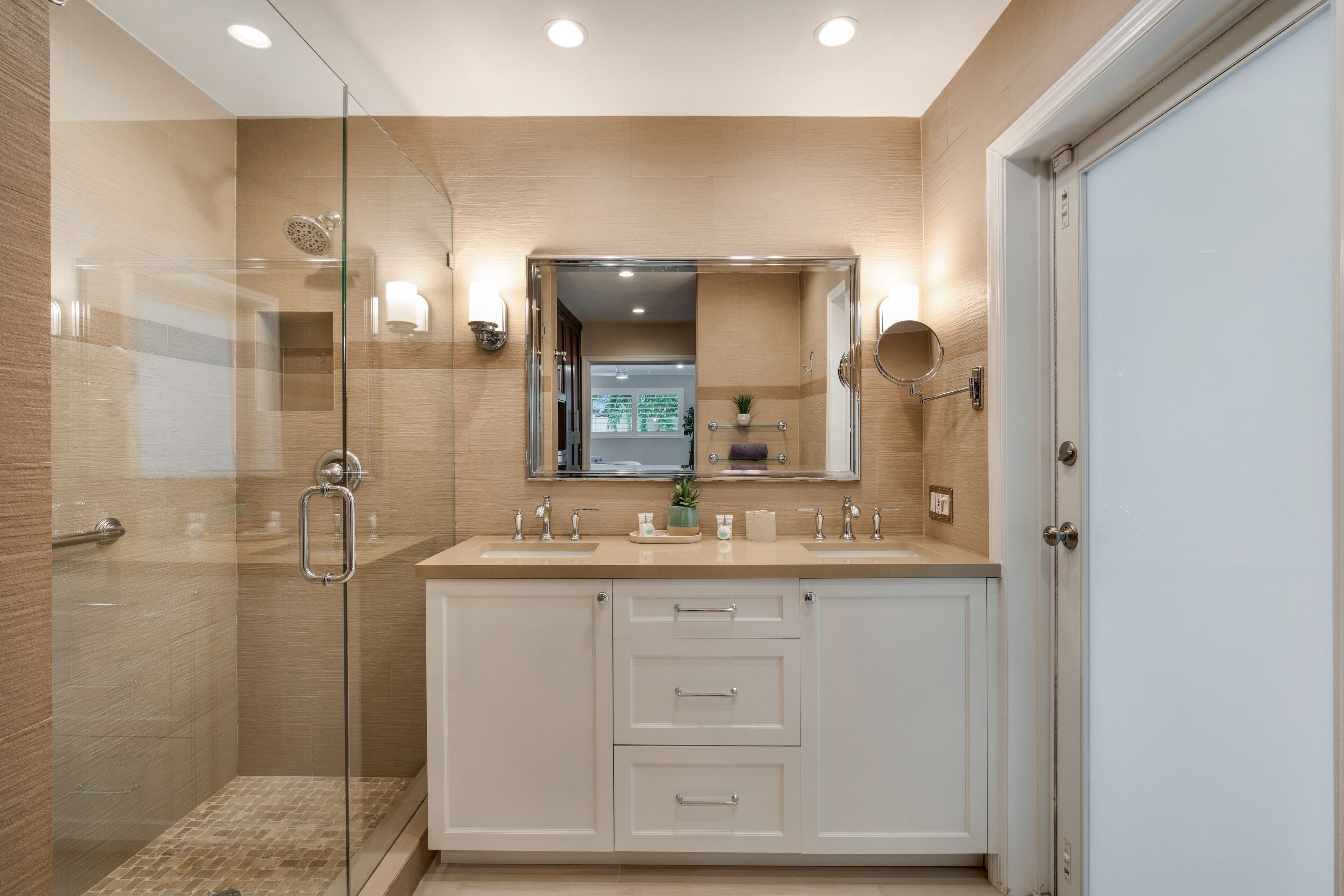 A modern bathroom with a glass-enclosed shower, a double sink vanity, and a large mirror above the vanity.