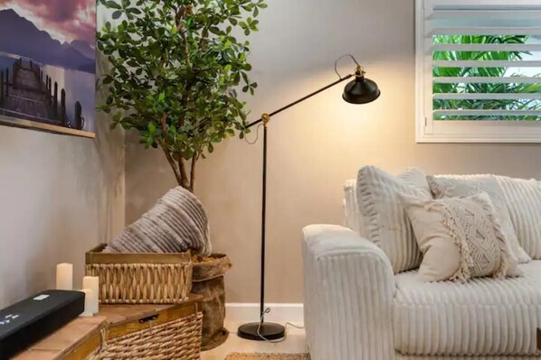 Un salon chaleureux avec un canapé blanc, une lampe sur pied, une plante et un panier décoratif.