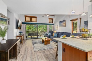 A spacious living area with a balcony, a dining area, and a kitchen. - Tropical Treehouse Near the Beach (Koloa)