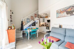 Um apartamento moderno com uma escada que dá para uma sala de jantar, uma sala de estar com sofá e uma cozinha.