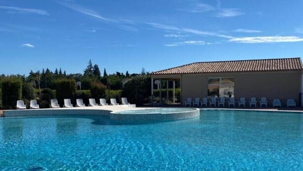 A clear blue pool with lounge chairs and a building with a tiled roof. - Bastidon at the foot of Ventoux with shared swimming pools and Wi-Fi (Aubignan)