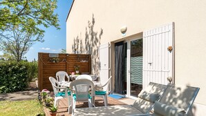 A patio with two lounge chairs, a table with chairs, and a wooden fence with potted plants. - Bastidon at the foot of Ventoux with shared swimming pools and Wi-Fi (Aubignan)