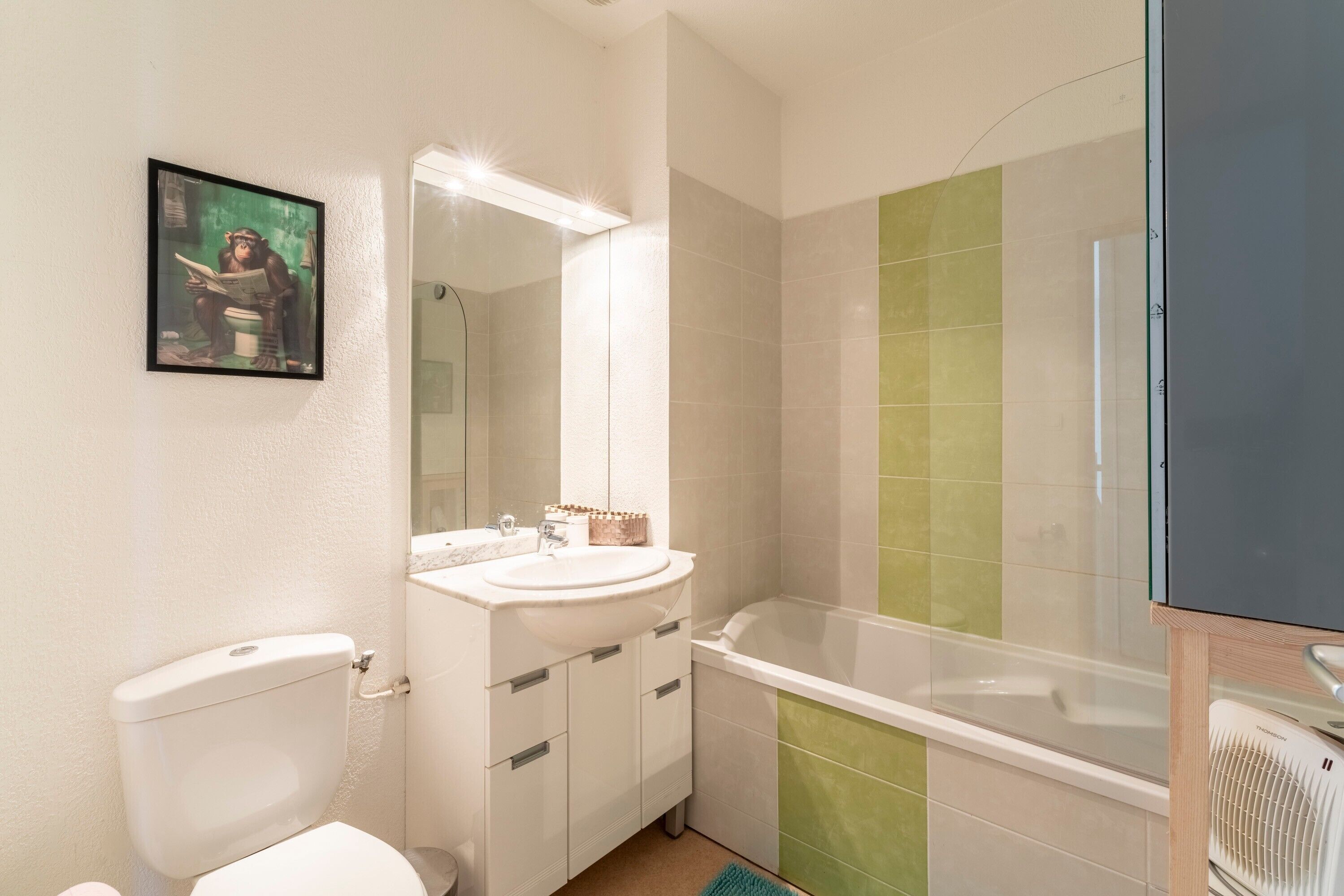 A bathroom with a toilet, sink, mirror, and bathtub.