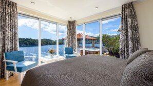 A bedroom with a large bed, a view of a lake, and a balcony with a table and chairs. - Spacious 5 bedroom Villa K with sea access  (Zaton)