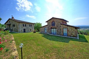 A stone house with a sloped roof, a small garden, and a clear sky. - Villa Quercina by MMega (Pergine Valdarno)