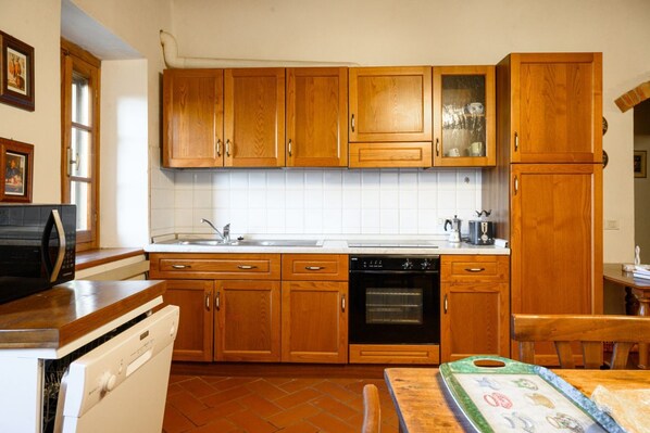 Una cocina con armarios de madera, lavavajillas, horno y microondas.