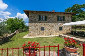 A stone building with a tiled roof, green shutters, and a red fence. - Villa Quercina by MMega (Pergine Valdarno)
