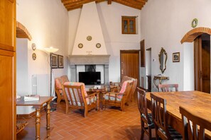 Un comedor con mesa y sillas de madera, chimenea y televisor.