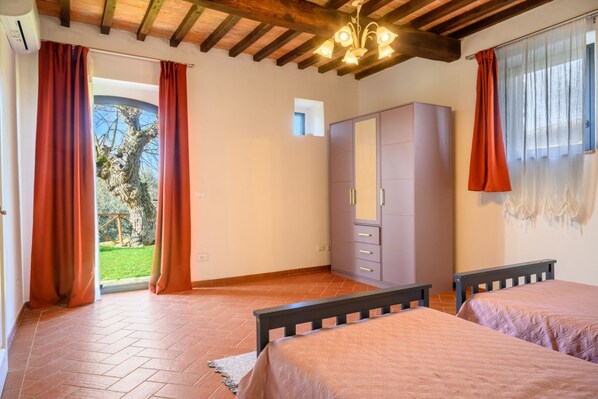 Une chambre avec deux lits, une armoire, un ventilateur de plafond et une vue sur l’extérieur.