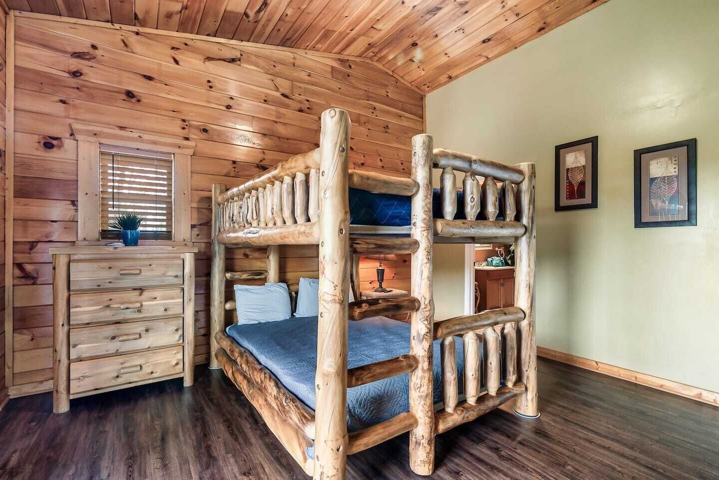 A bunk bed with a wooden frame, a dresser with drawers, and a window with blinds.