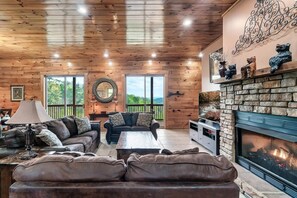 A cozy living room with wooden walls, a fireplace, and a large TV.