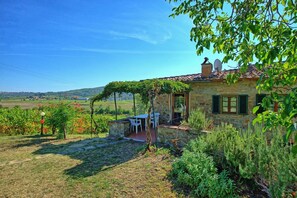 A stone house with a garden, outdoor seating, and a view of the countryside.