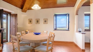 Un coin repas avec une table ronde en bois, des chaises, un bol bleu et des tableaux encadrés accrochés au mur.