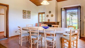 Un'area pranzo con tavolo e sedie in legno, un lampadario e un caminetto.