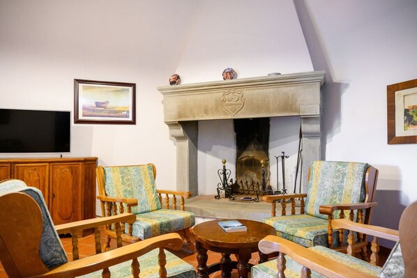 A living room with a fireplace, wooden furniture, and a television.