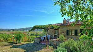 Une maison en pierre avec un jardin, un espace extérieur aménagé et une vue sur la campagne.