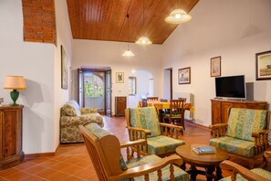 A spacious living room with wooden furniture, a dining area, and a television.