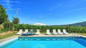 Une piscine avec des chaises longues et un parasol blanc.