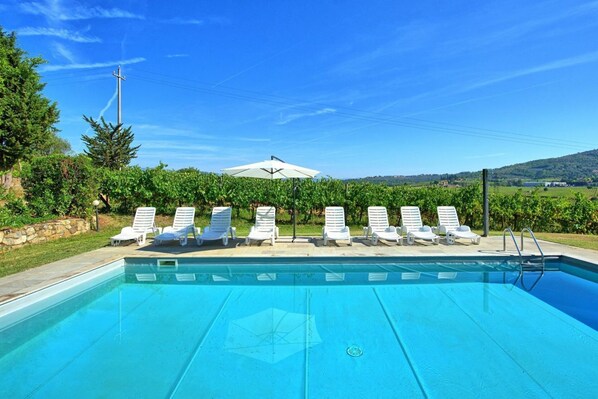 A swimming pool with lounge chairs and a white umbrella.