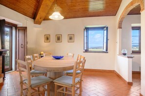 A dining area with a round wooden table, chairs, a blue bowl, and framed pictures on the wall.