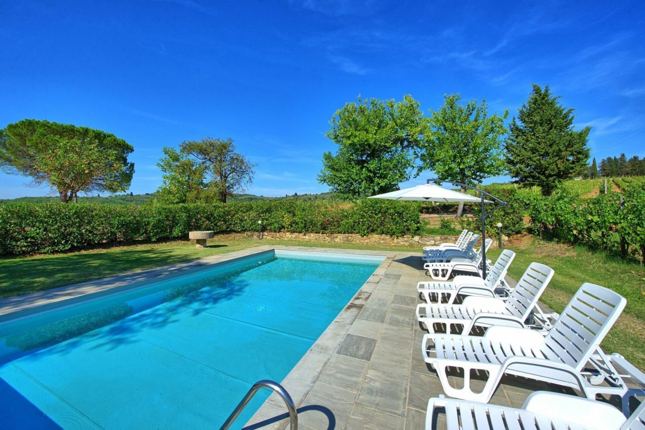 A swimming pool with lounge chairs and a pergola.