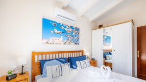 A hotel room with a bed, a nightstand, a wall-mounted air conditioner, a painting of a tree, and a wooden door. - Country House 'Son Macia' with Mountain View, Wi-Fi and Air Conditioning (Selva)