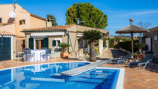 A swimming pool with lounge chairs, a table, and a thatched umbrella. - Country House 'Son Macia' with Mountain View, Wi-Fi and Air Conditioning (Selva)
