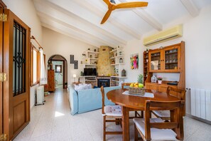 Un vaste espace de vie comprenant un coin salon avec cheminée, une table à manger et un coin cuisine doté de meubles en bois.
