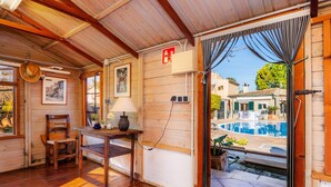 A wooden interior with a wooden ceiling, a table with a lamp, a chair, a framed picture, and a door leading outside. - Country House 'Son Macia' with Mountain View, Wi-Fi and Air Conditioning (Selva)