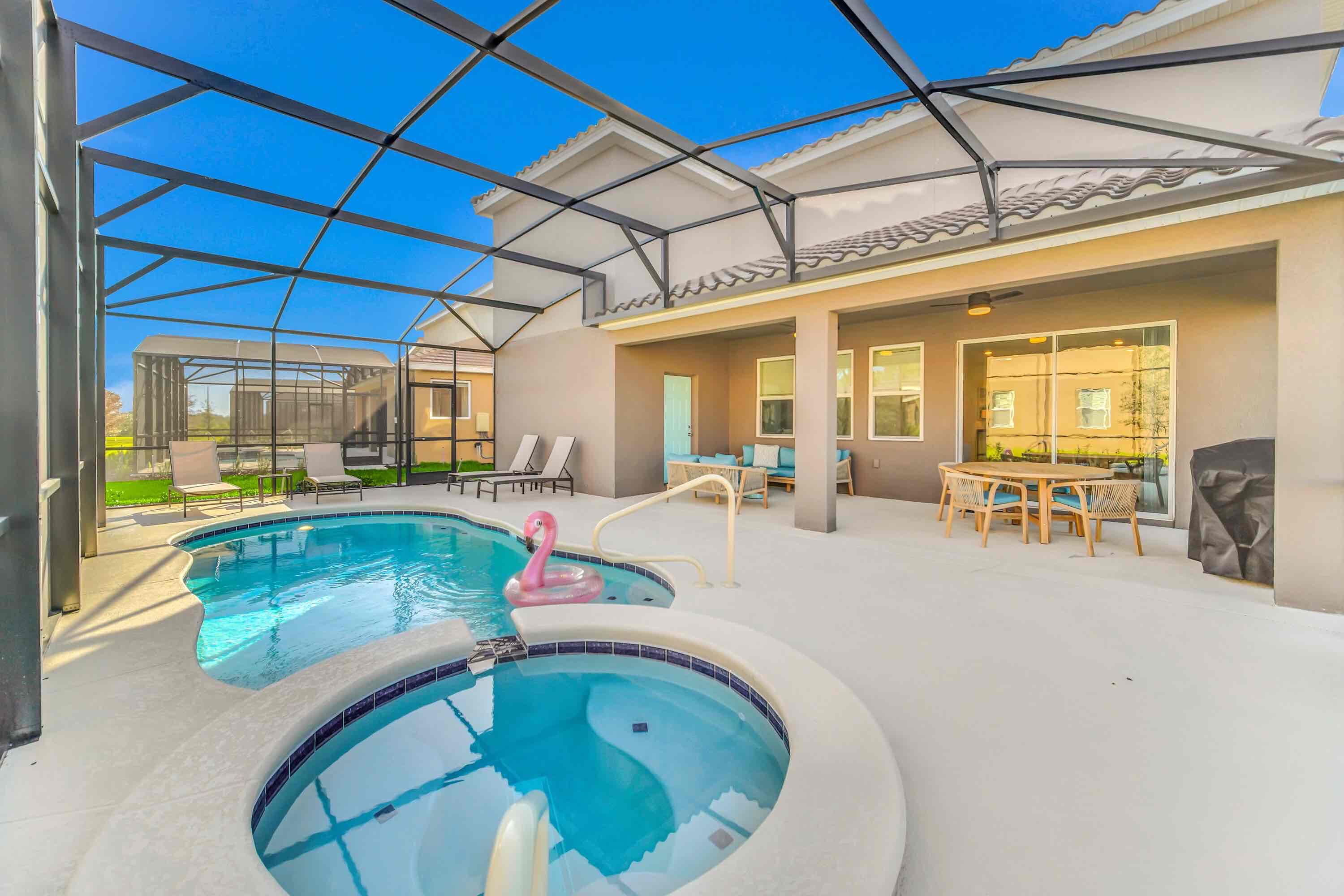 A swimming pool with a hot tub, lounge chairs, and a covered patio area.