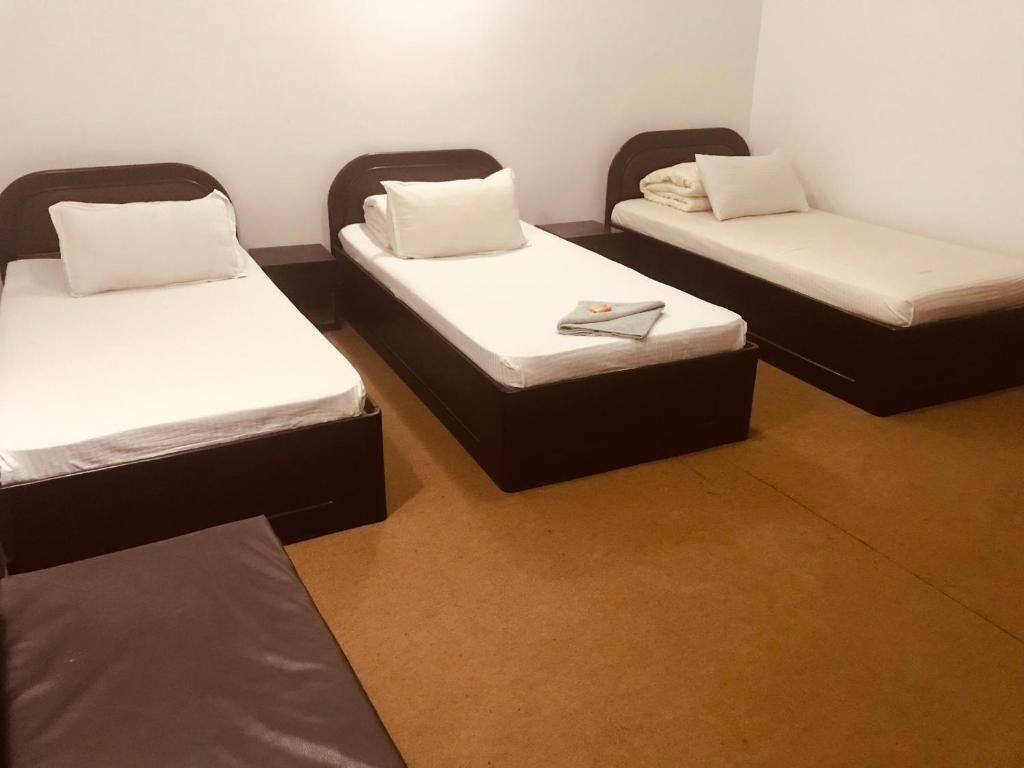 A room with three single beds, each with a mattress and pillow.