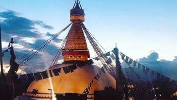 A traditional building with a conical roof and a large circular structure at the base, surrounded by flags.