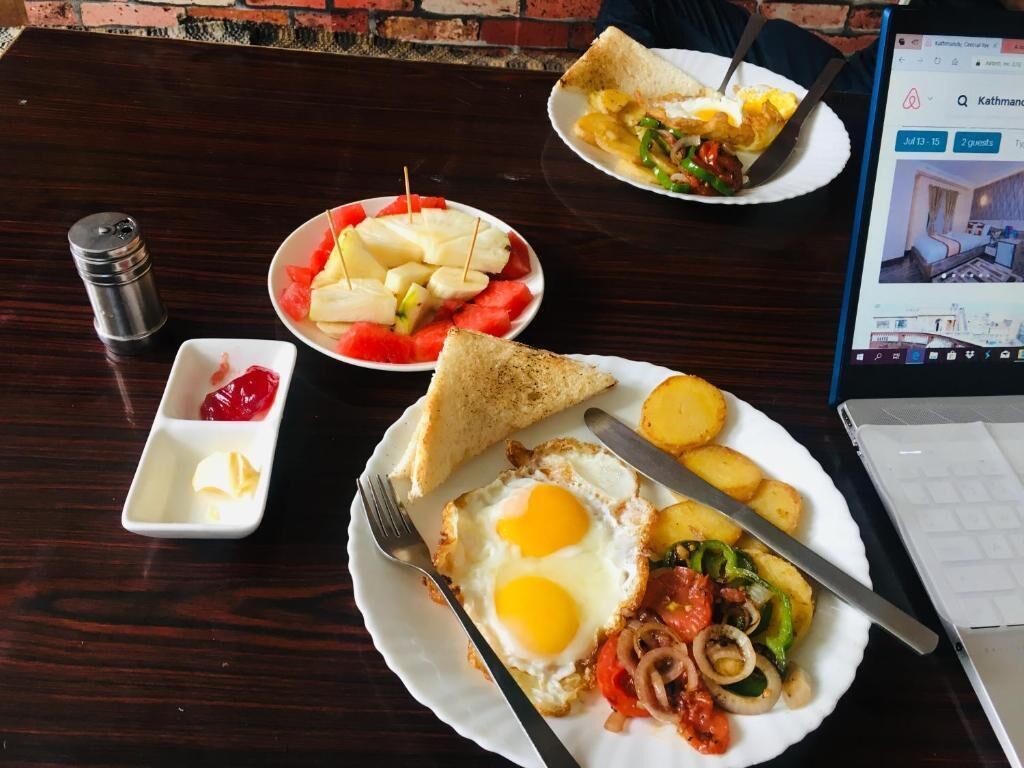 A breakfast setting with toast, eggs, tomatoes, onions, and potatoes on a wooden table.