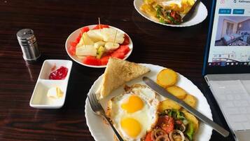 A breakfast setting with toast, eggs, tomatoes, onions, and potatoes on a wooden table.