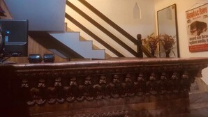 Una escalera con barandilla de madera y un aplique en la pared.